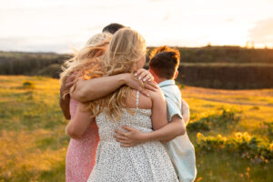 Family of four hugging at sunset in Hood River, Oregon. Hood River Waterfront Park. 