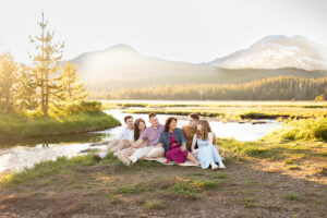 Family of 6 sitting in a meadow in front of South Sister, Oregon. 