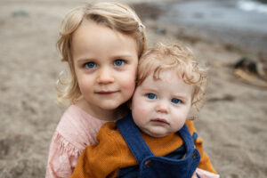 Oregon coast photography takes an image of a toddler with an infant sibling on a beach near Pacific City, Oregon. Photo is featured in a blog post about how much family photography cost?