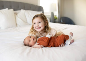 A little girl holding her newborn baby brother. DIY newborn photos ideas. 