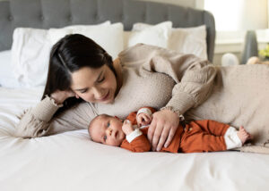 Mom and newborn lie on bed. Newborn photo ideas. 