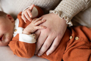 Mothers hand under newborn baby's hand during a newborn photo shoot. 