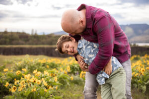 Dad and son hugging in wildflowers at Rowena Crest for family photos. 