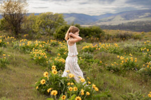 Little girl walking through yellow Oregon wildflowers at Rowena Crest. 