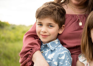 Young boy smiling at the camera with his moms hand around him at Rowena Crest for family photos. 