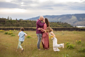 Parents kiss while kids run around them in wildflowers near Mosier Oregon.