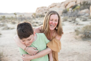 Mom hugging young son in the desert at sunset for Joshua Tree family photos. 