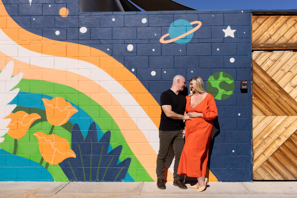Pregnant couple in front of colorful mural in Palm Springs, California.