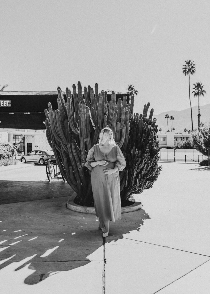 Black and white photo of pregnant woman standing in front of the Ace hotel for a Palm Springs photo shoot.