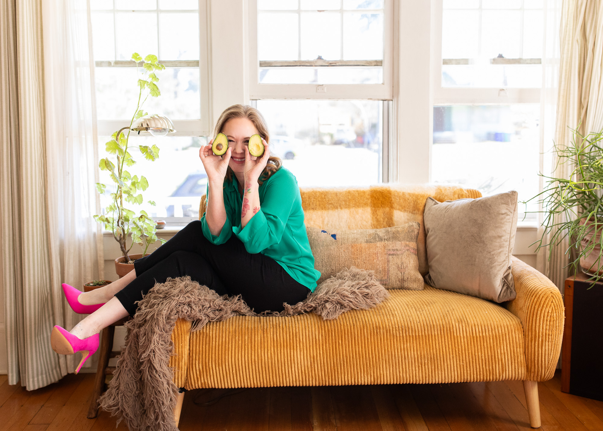 Physician sitting on a couch with avocados in front of her eyes.