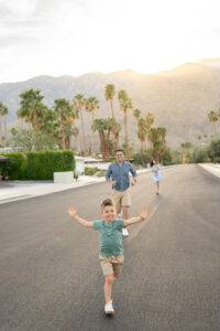 Young boy smiles as he runs freely at sunset in front of the San Jancinto mountains at a Palm Springs Pink Door photoshoot 