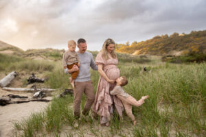 Family walking barefoot along the beach during golden hour — natural and timeless pregnancy photoshoot idea.