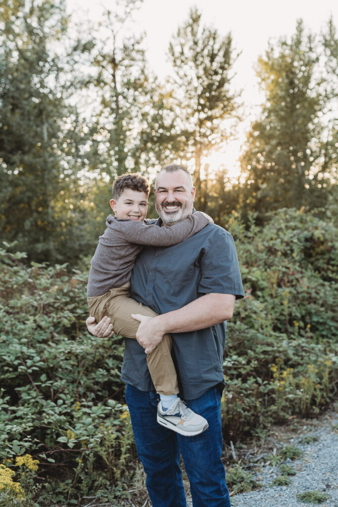 Dad holds little boy on his hip in a park in Ridgefield, Washington 