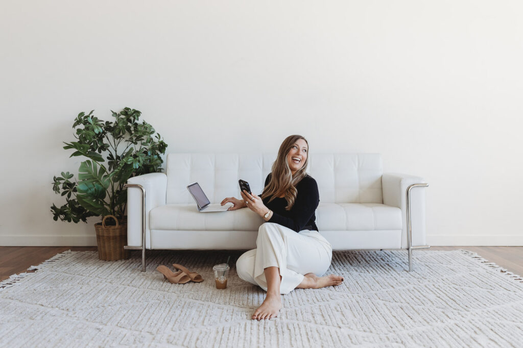 Small business owner laughing while working on her phone during a branding session.